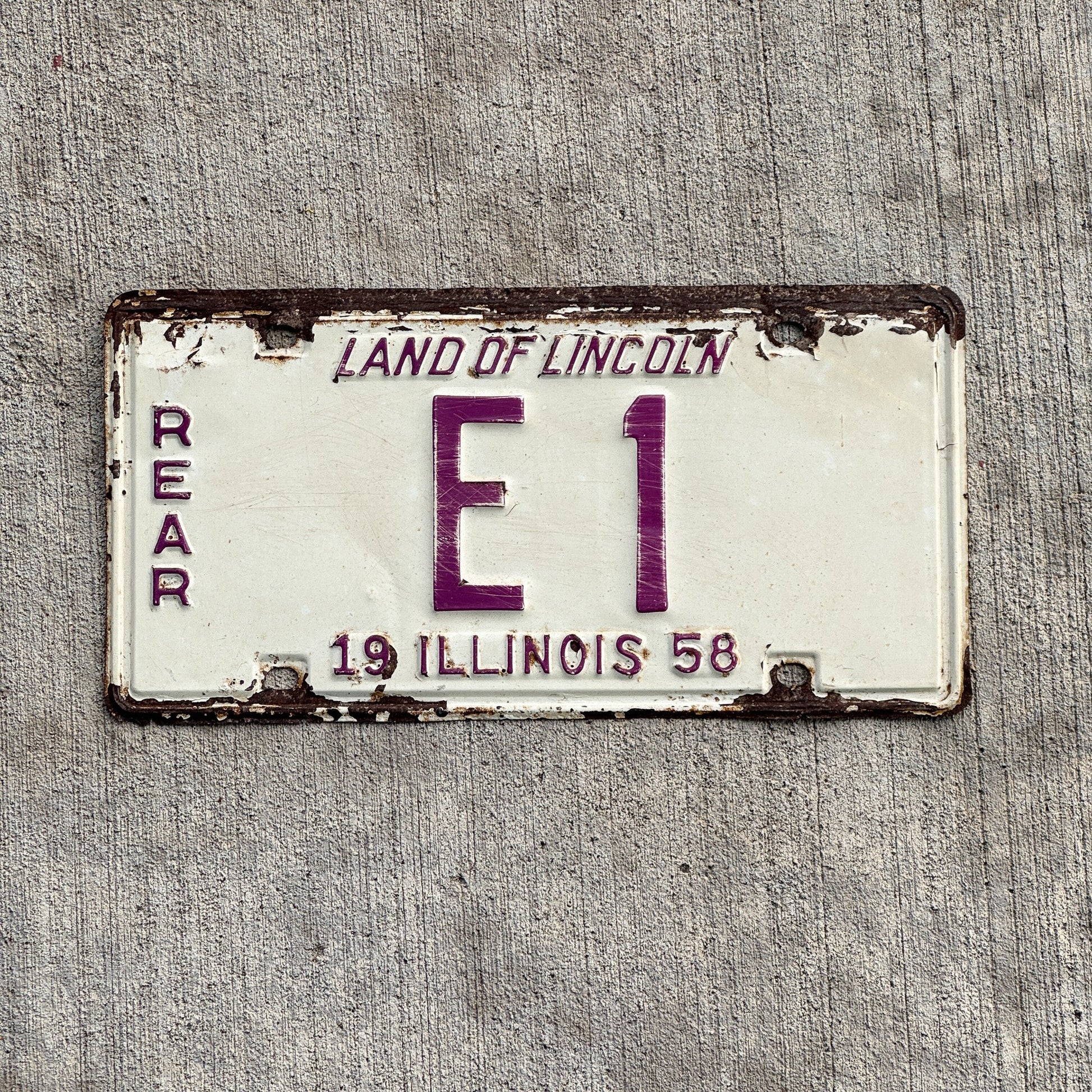 Photo of a 1958 Illinois Truck License Plate Auto Tag Garage Decor Vintage Rear Low Number Single Digit E 1 with original patina