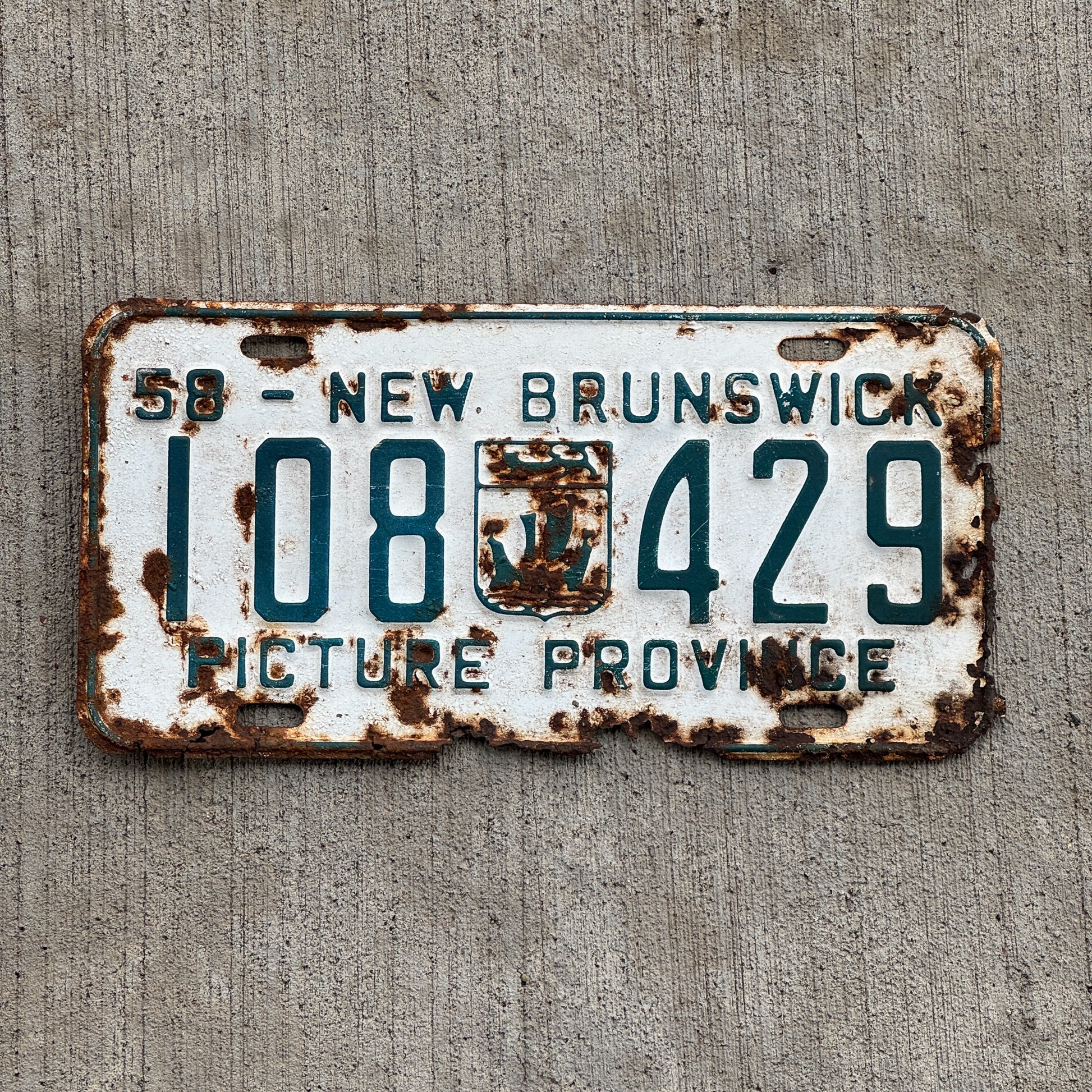 Photo of a 1958 New Brunswick License Plate Auto Tag Garage Decor Vintage Provincial Coat of Arms 108 429 with original patina