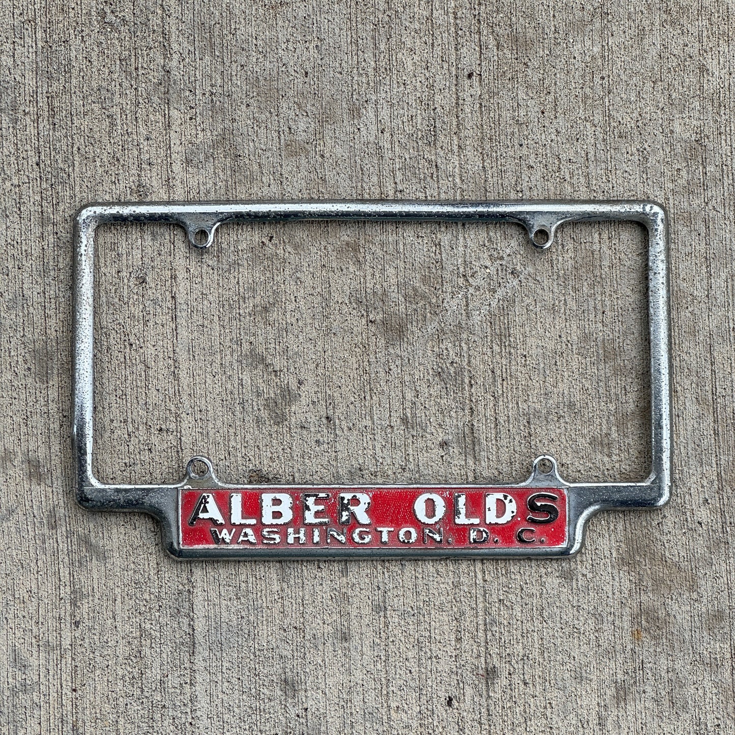 Photo of a 1960 Era Alber Olds Washington DC License Plate Frame Auto Tag Garage Decor Vintage Oldsmobile Dealer Dealership with original patina