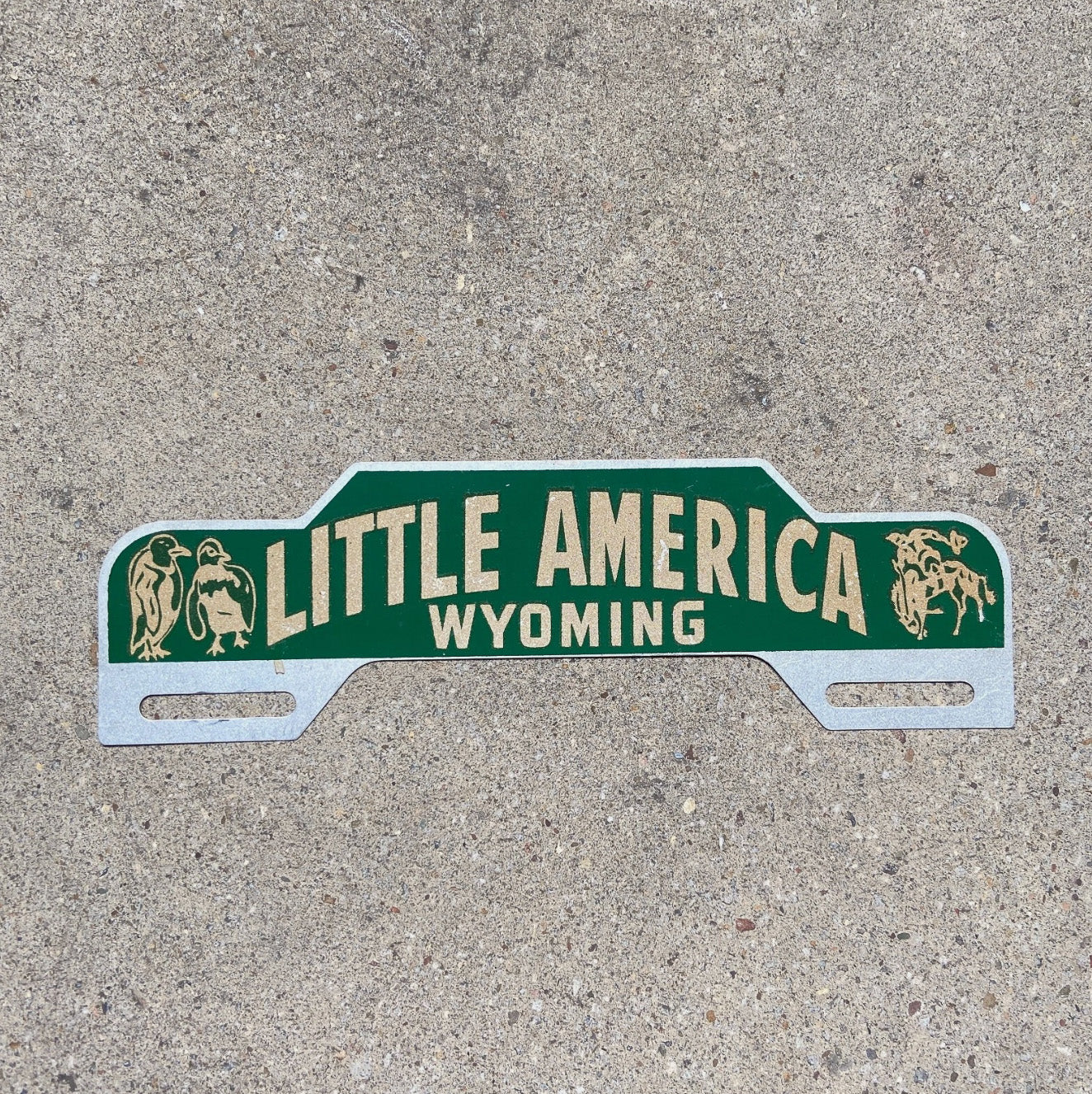 Photo of a 1960 Era Little America Wyoming License Plate Topper Auto Tag Garage Decor Vintage Reflective Smaltz Paint with original patina