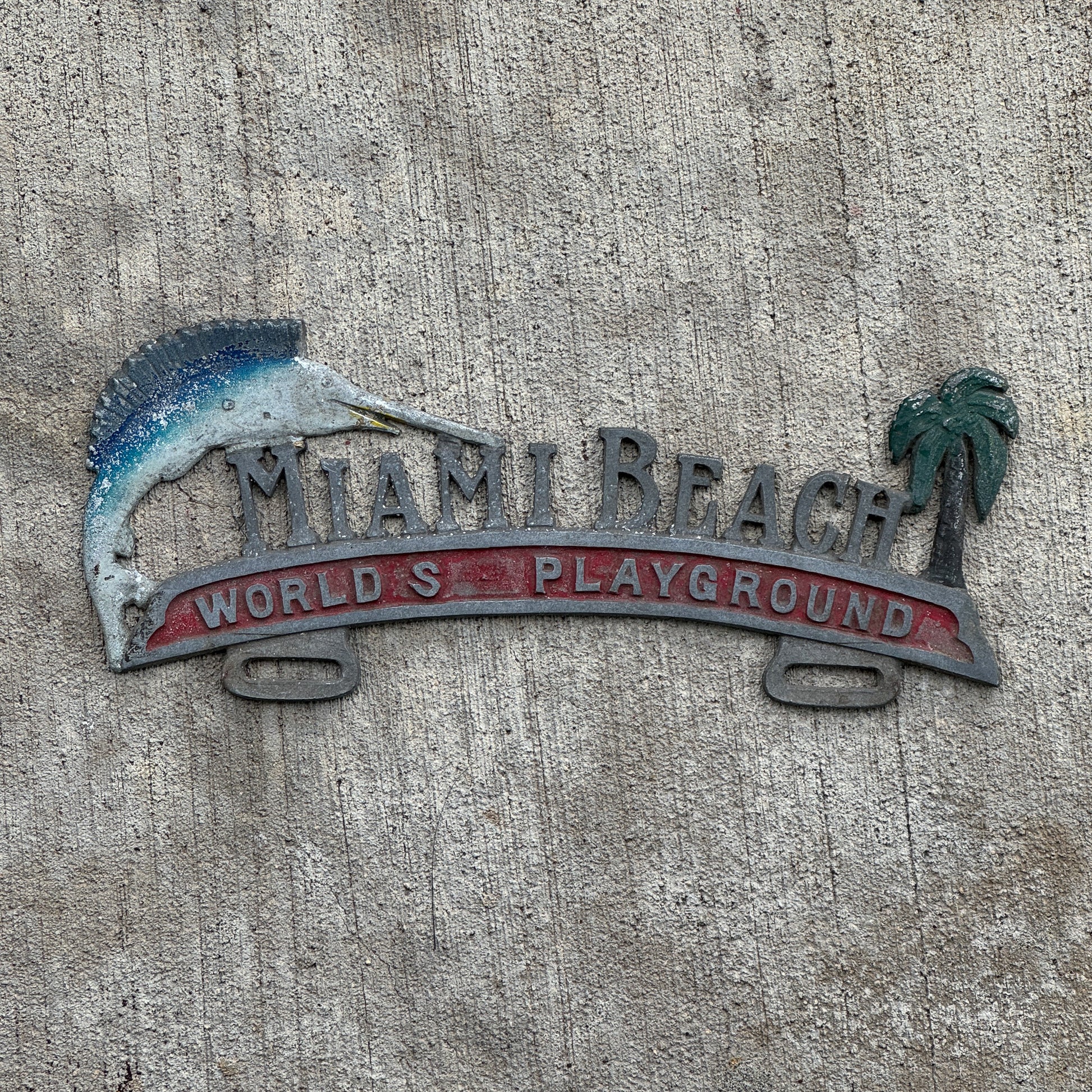 Photo of a 1960 Era Miami Beach Florida License Plate Topper Auto Tag Garage Decor Vintage World's Playground Cast Aluminum with original patina