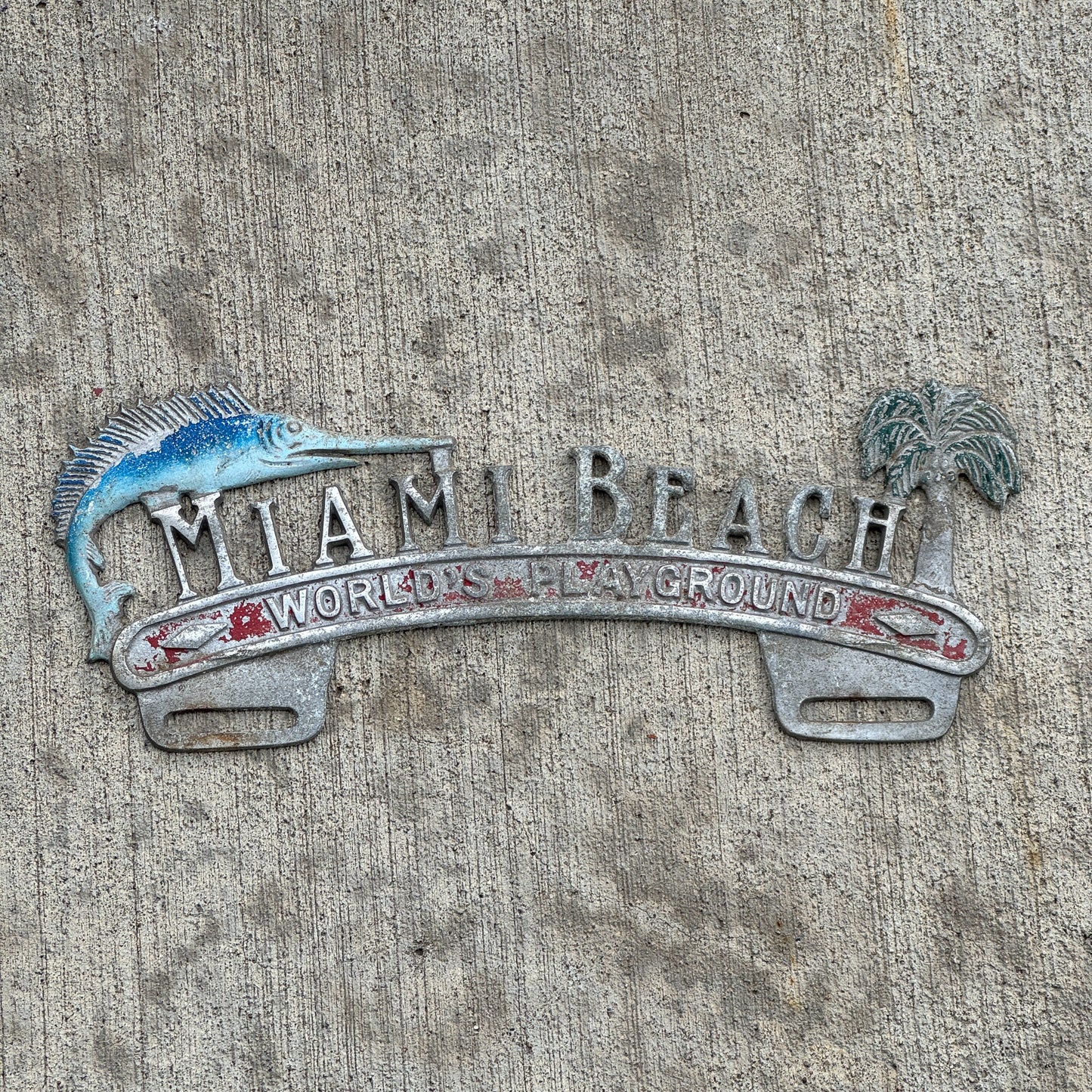 Photo of a 1960 Era Miami Beach Florida License Plate Topper Auto Tag Garage Decor Vintage World's Playground Cast Aluminum with original patina