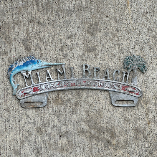 Photo of a 1960 Era Miami Beach Florida License Plate Topper Auto Tag Garage Decor Vintage World's Playground Cast Aluminum with original patina