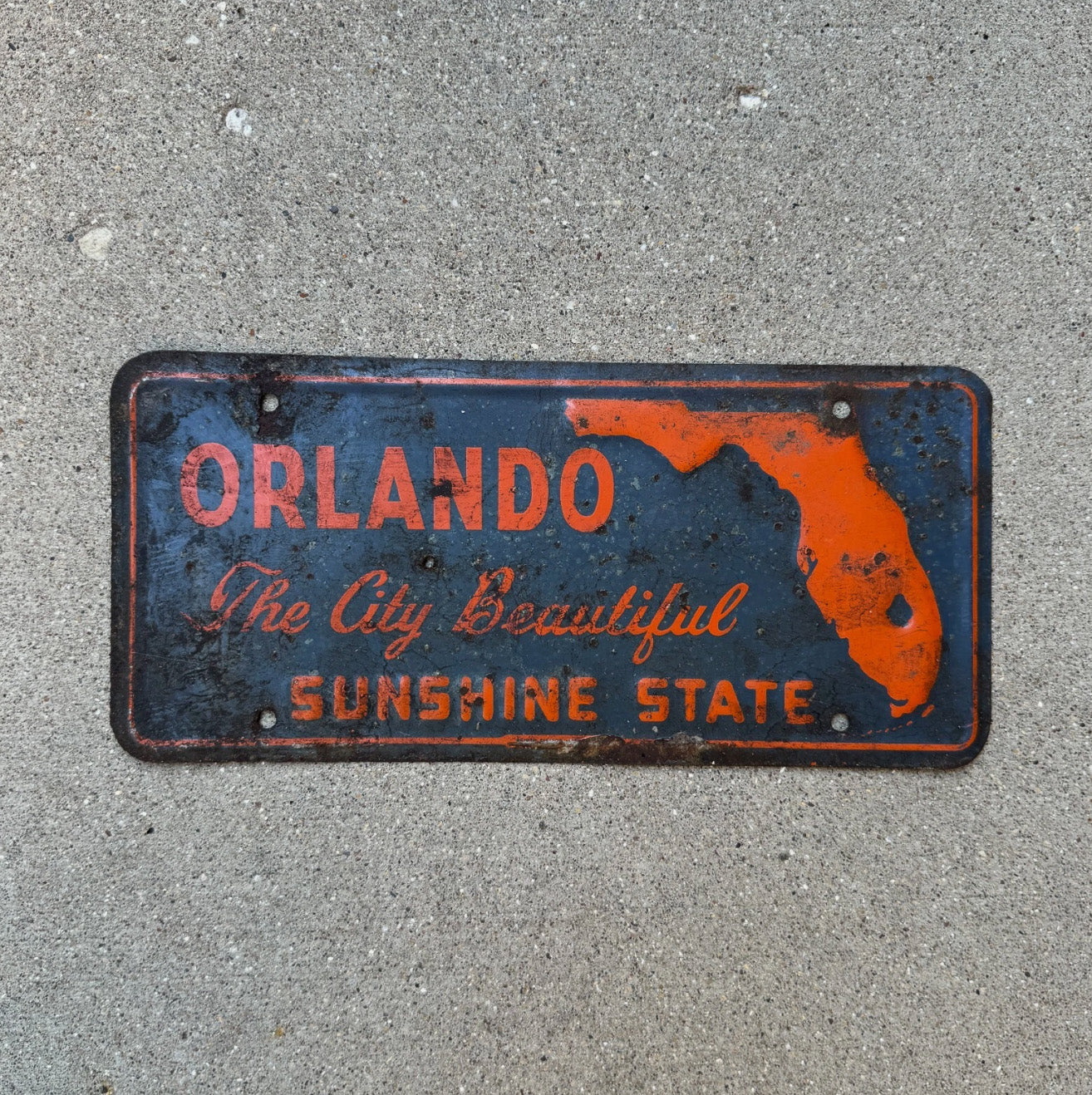 Photo of a 1960 Era Orlando Florida Booster License Plate Auto Tag Garage Decor Vintage Orange Blue Sunshine State with original patina