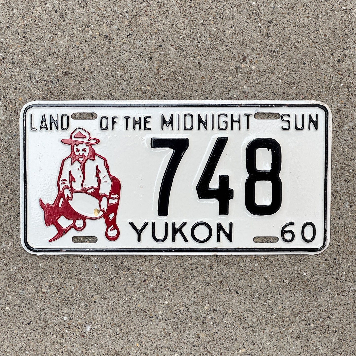 Photo of a 1960 Yukon License Plate Auto Tag Garage Decor Vintage Prospector Gold Miner Low Number Three Digit 748 with original patina