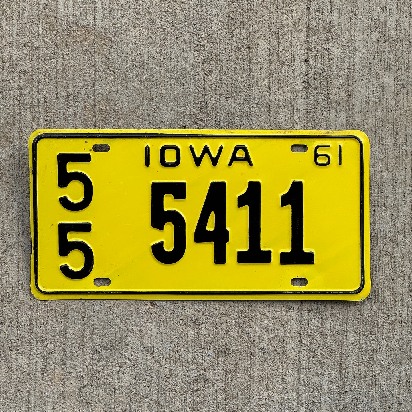 Yellow 1961 Iowa license plate with black text on a gray textured background