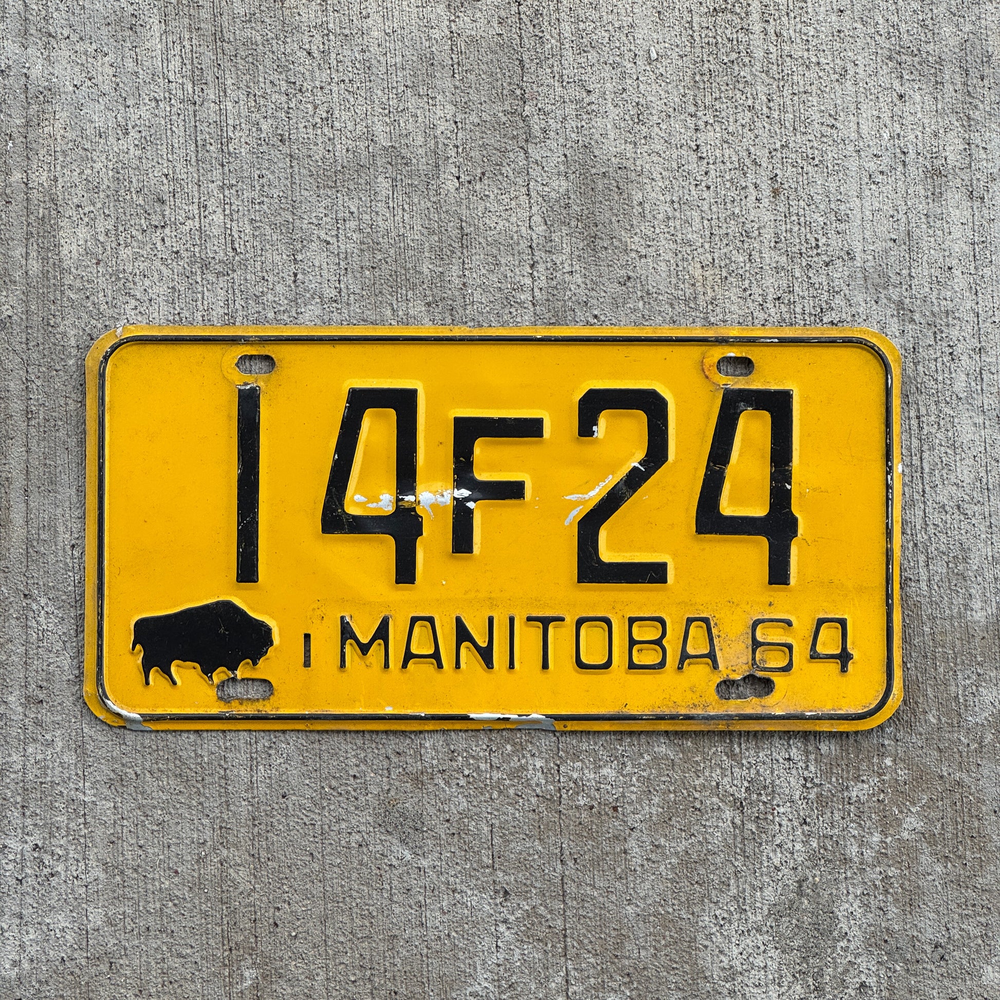Photo of a 1964 Manitoba License Plate Auto Tag Garage Decor Vintage Buffalo Bison 14 F 24 with original patina