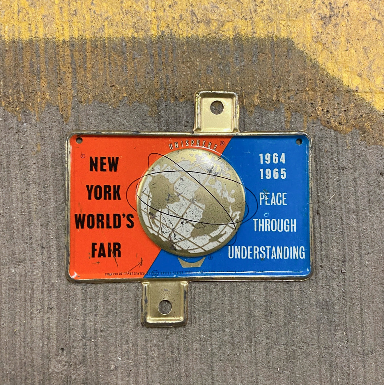 Photo of a 1964 New York World's Fair New York License Plate Topper Auto Tag Garage Decor Vintage Unisphere Embossed with original patina