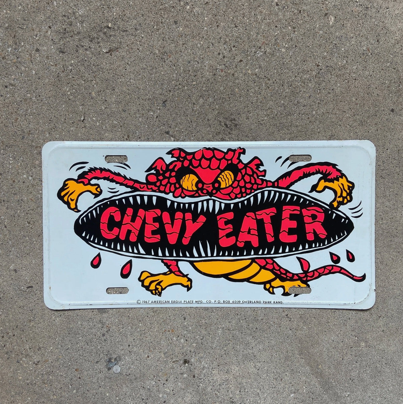 Photo of a 1967 Chevy Eater Booster License Plate Auto Tag Garage Decor Vintage Chevrolet Rat Fink Rat Rod American Eagle with original patina