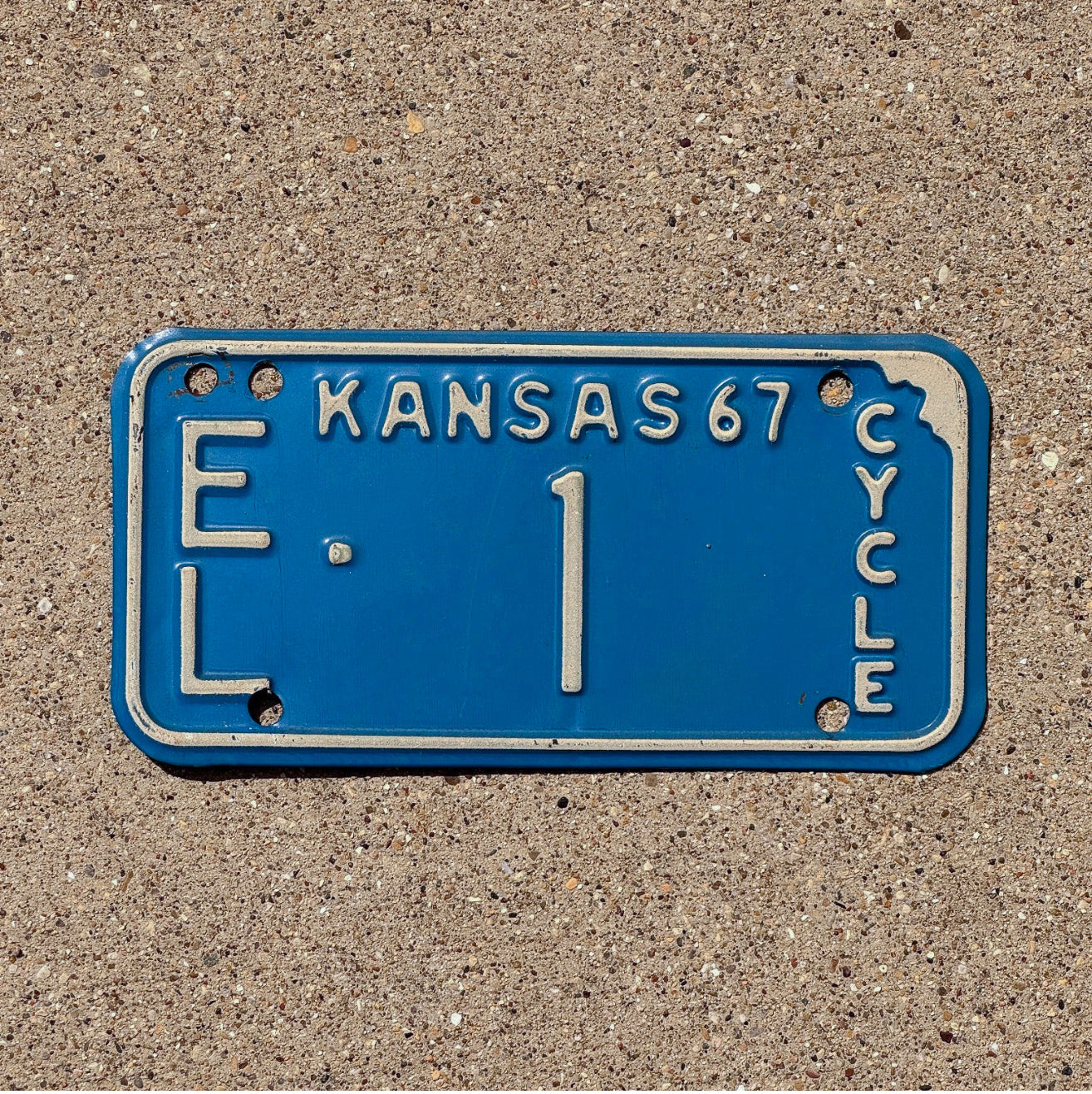 Photo of a 1967 Kansas Motorcycle License Plate Auto Tag Garage Decor Vintage Low Number Single Digit Ellis County EL 1 with original patina