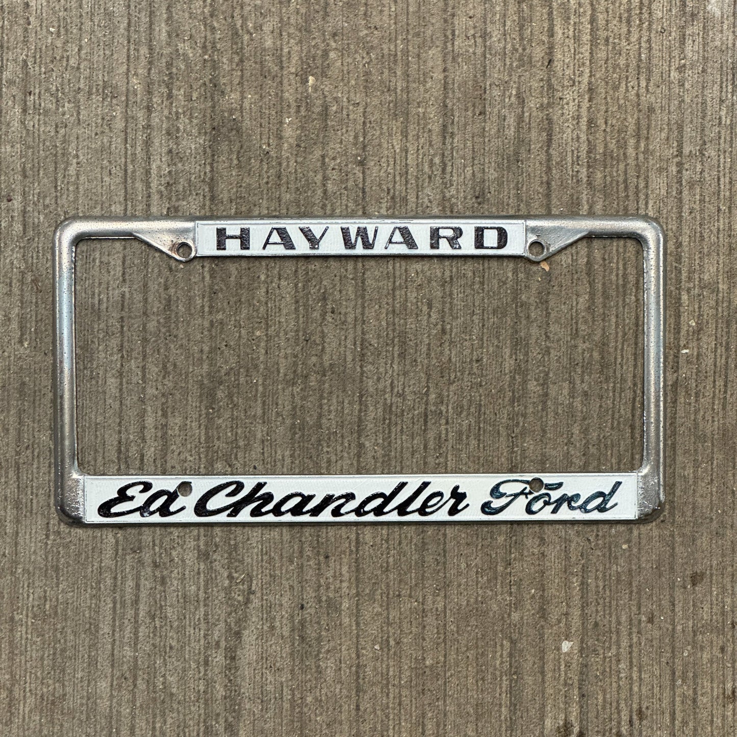 Photo of a 1970 Era California License Plate Frame Auto Tag Garage Decor Vintage Hayward Metal Ed Chandler Ford with original patina