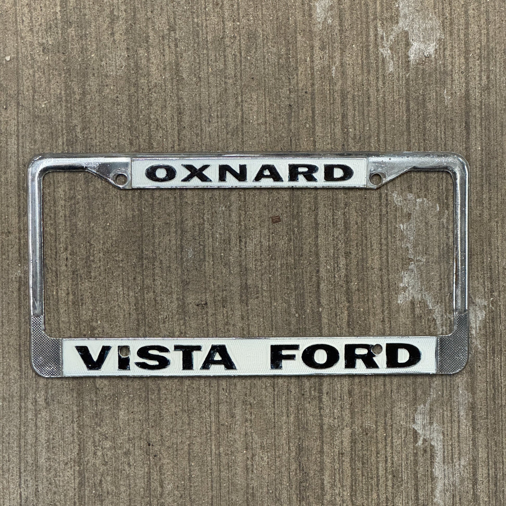 Photo of a 1970 Era California License Plate Frame Auto Tag Garage Decor Vintage Oxnard Metal Vista Ford with original patina