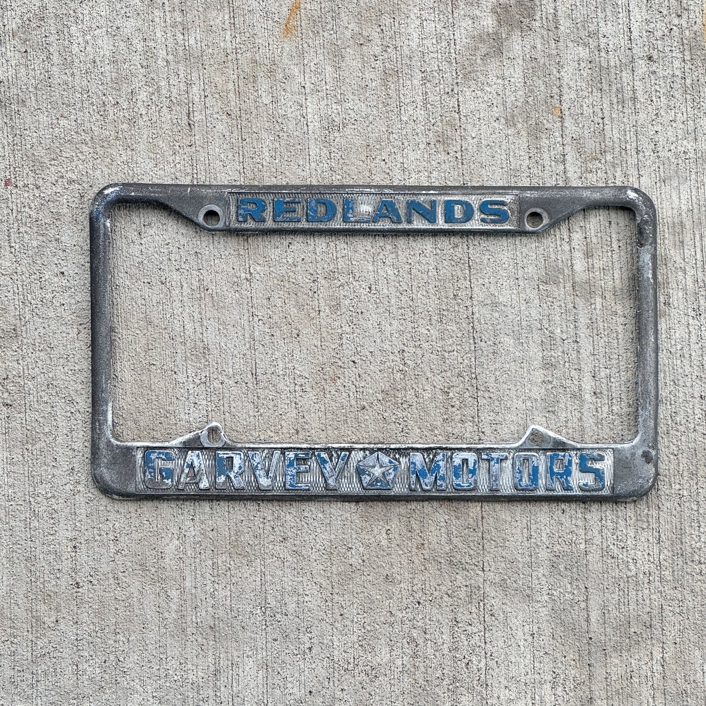 Photo of a 1970 Era California License Plate Frame Auto Tag Garage Decor Vintage Redlands Garvey Motors Chrysler and Plymouth with original patina