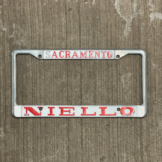 Photo of a 1970 Era California License Plate Frame Auto Tag Garage Decor Vintage Sacramento Metal Niello BMW Dealer with original patina