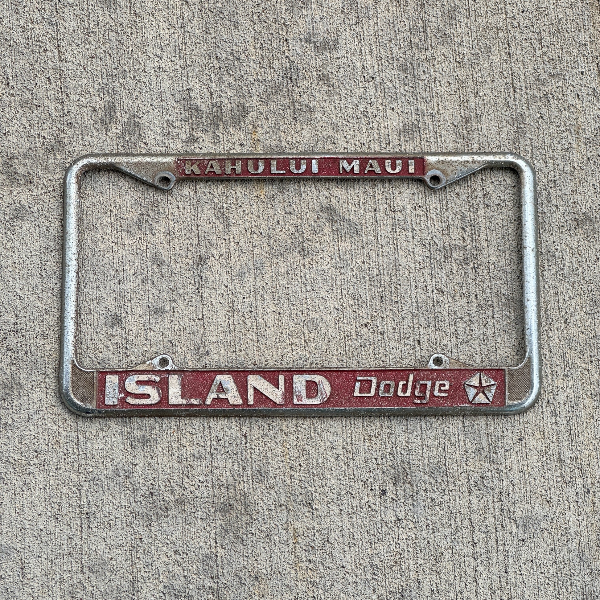 Photo of a 1970 Era Kahului Maui Hawaii License Plate Frame Auto Tag Garage Decor Vintage Island Dodge Dealer with original patina