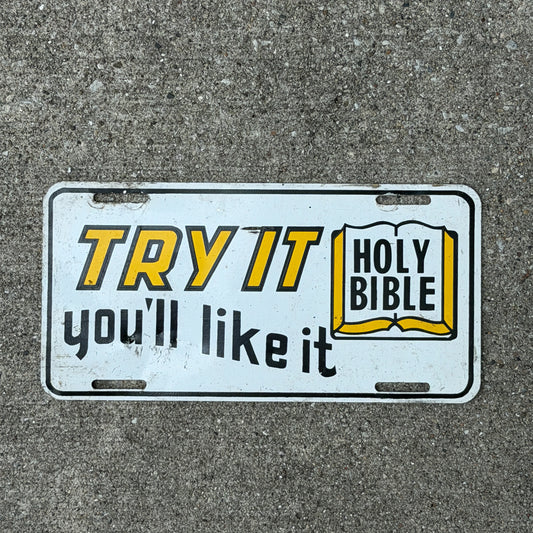 Photo of a 1970 Era Try It You'll Like It HOLY BIBLE Booster License Plate Auto Tag Garage Decor Vintage
 Religious Christian Metal with original patina