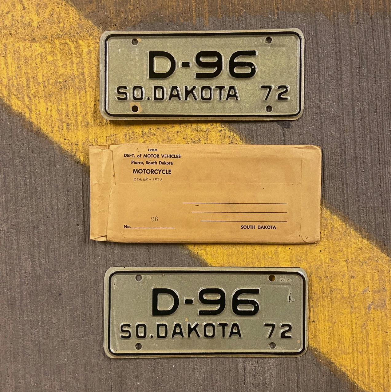Photo of a 1972 South Dakota Motorcycle Dealer License Plate Pair Auto Tag Garage Decor Vintage with Envelope Low Number Two Digit D 96 with original patina