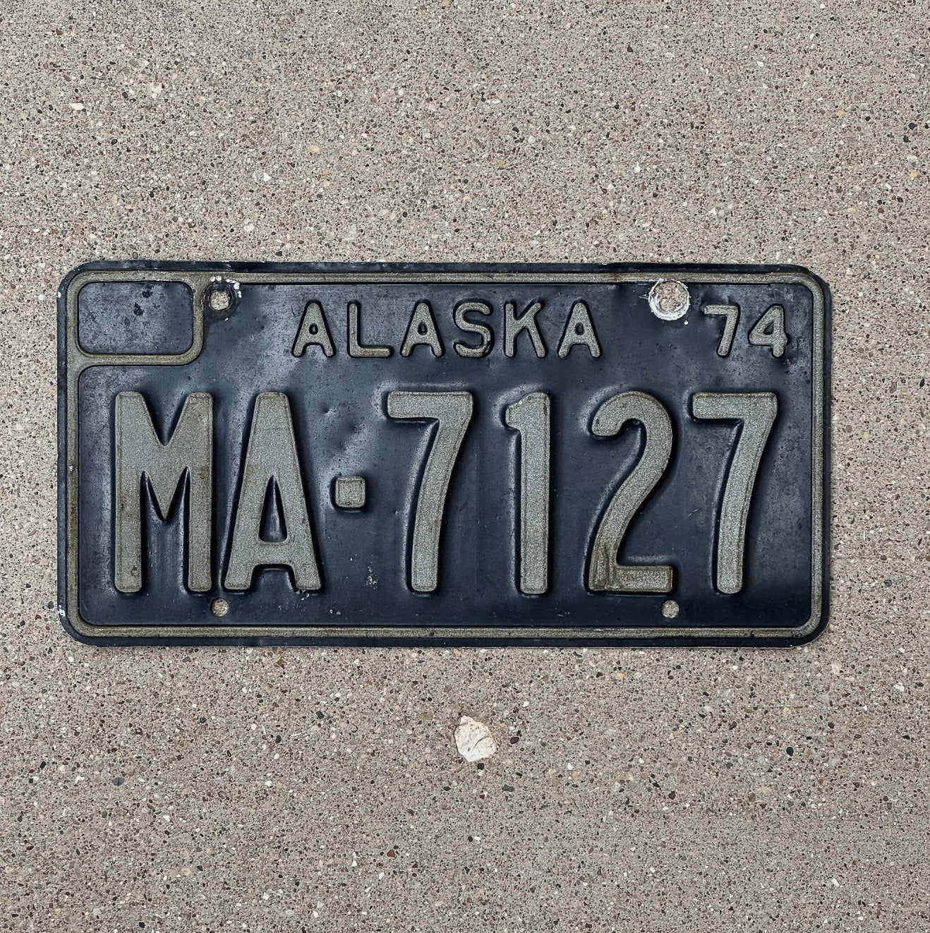 Photo of a 1974 Alaska Truck License Plate Auto Tag Garage Decor Vintage Black MA 7127 with original patina