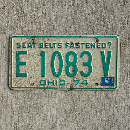 Image of 1974 1975 Ohio License Plate Auto Tag E 1083 V on a concrete background.