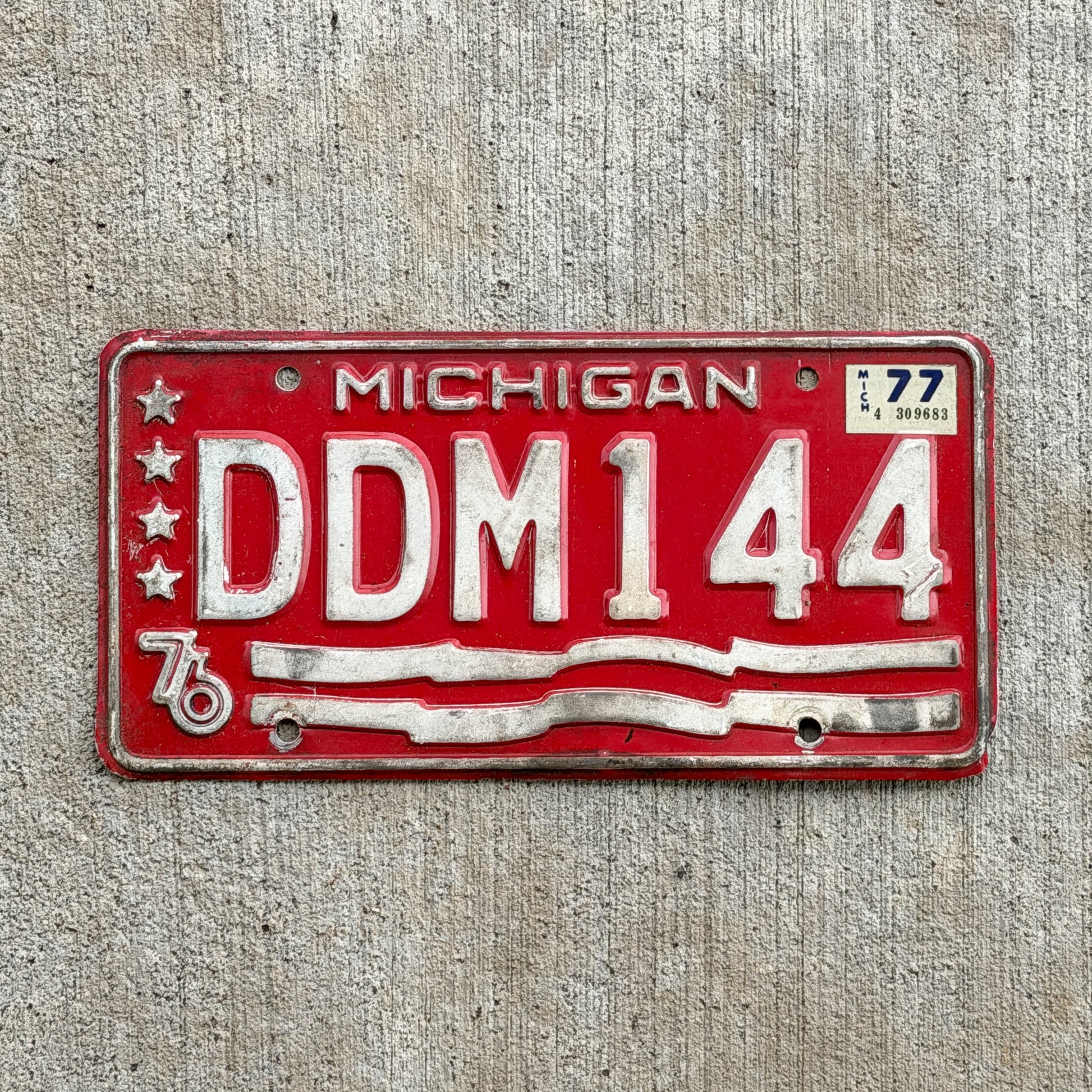 Photo of a 1976 1977 Michigan Error License Plate Auto Tag Garage Decor Vintage Bicentennial Misprint Lacking Blue DDM 144 with original patina