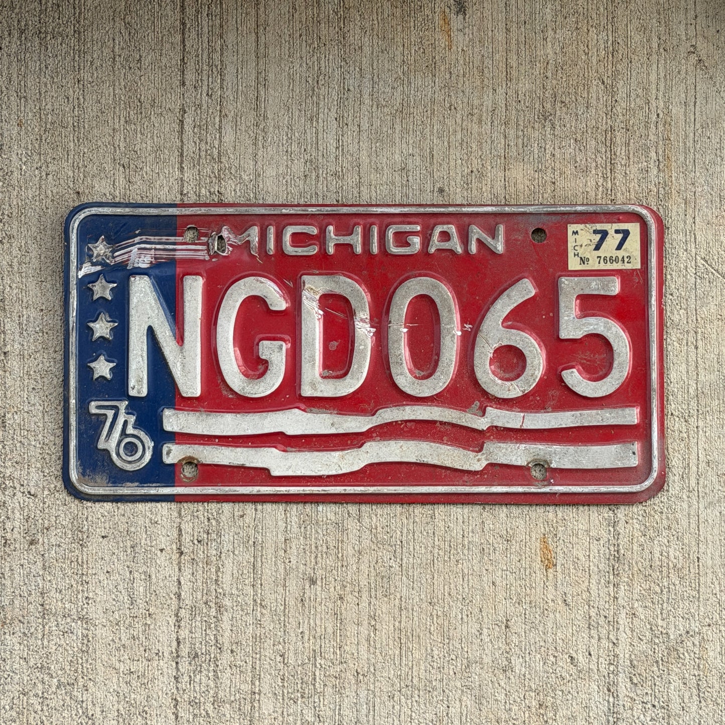 Photo of a 1976 1977 Michigan License Plate Auto Tag Garage Decor Vintage Bicentennial NGD 065 with original patina