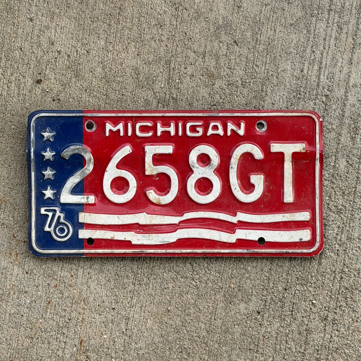 Photo of a 1976 Michigan Commercial License Plate Auto Tag Garage Decor Vintage Bicentennial 2658 GT with original patina