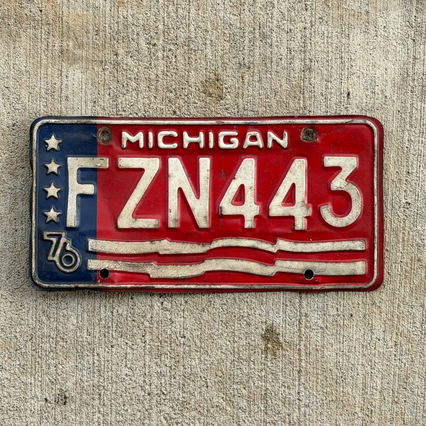 Photo of a 1976 Michigan License Plate Auto Tag Garage Decor Vintage Bicentennial FZN 443 with original patina