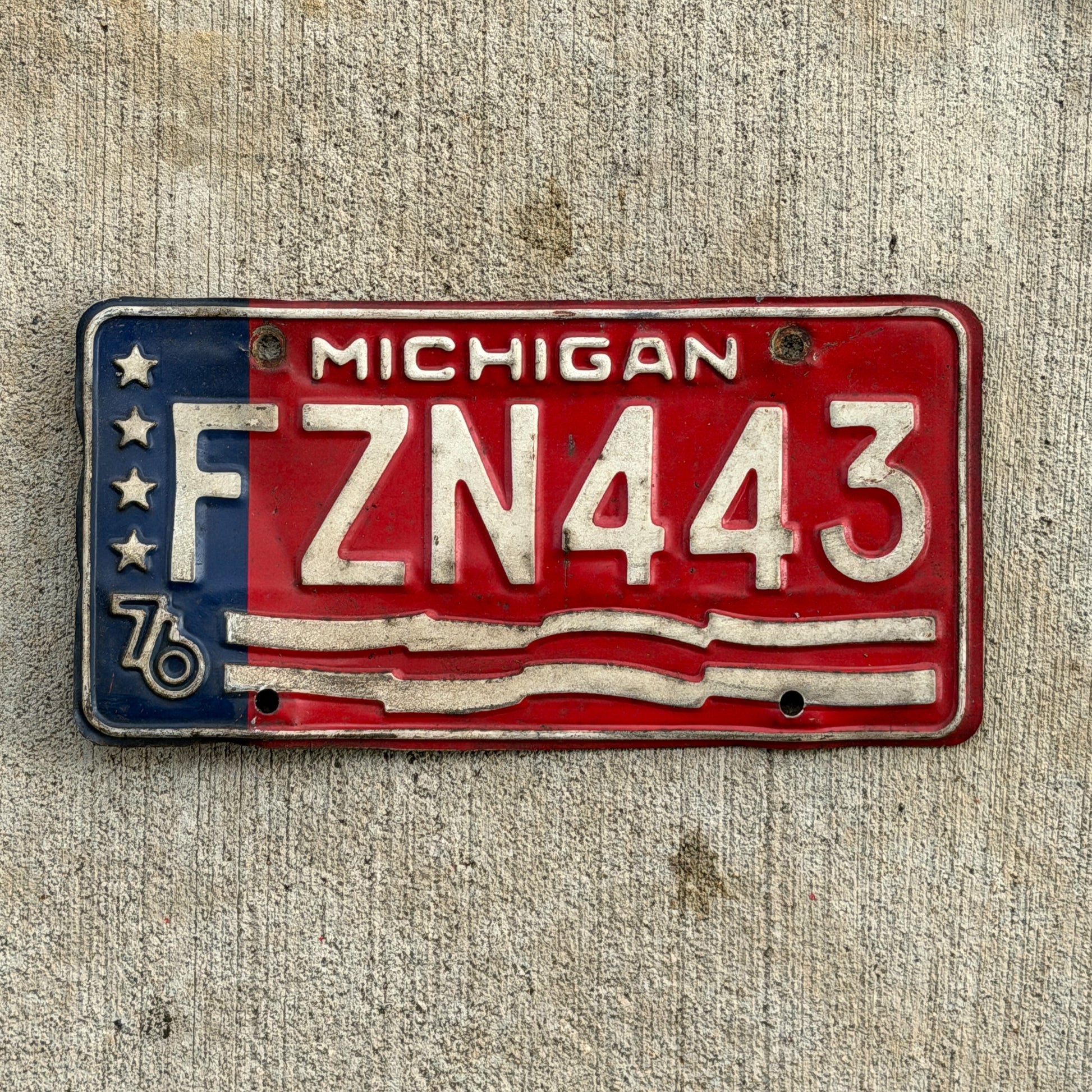 Photo of a 1976 Michigan License Plate Auto Tag Garage Decor Vintage Bicentennial FZN 443 with original patina