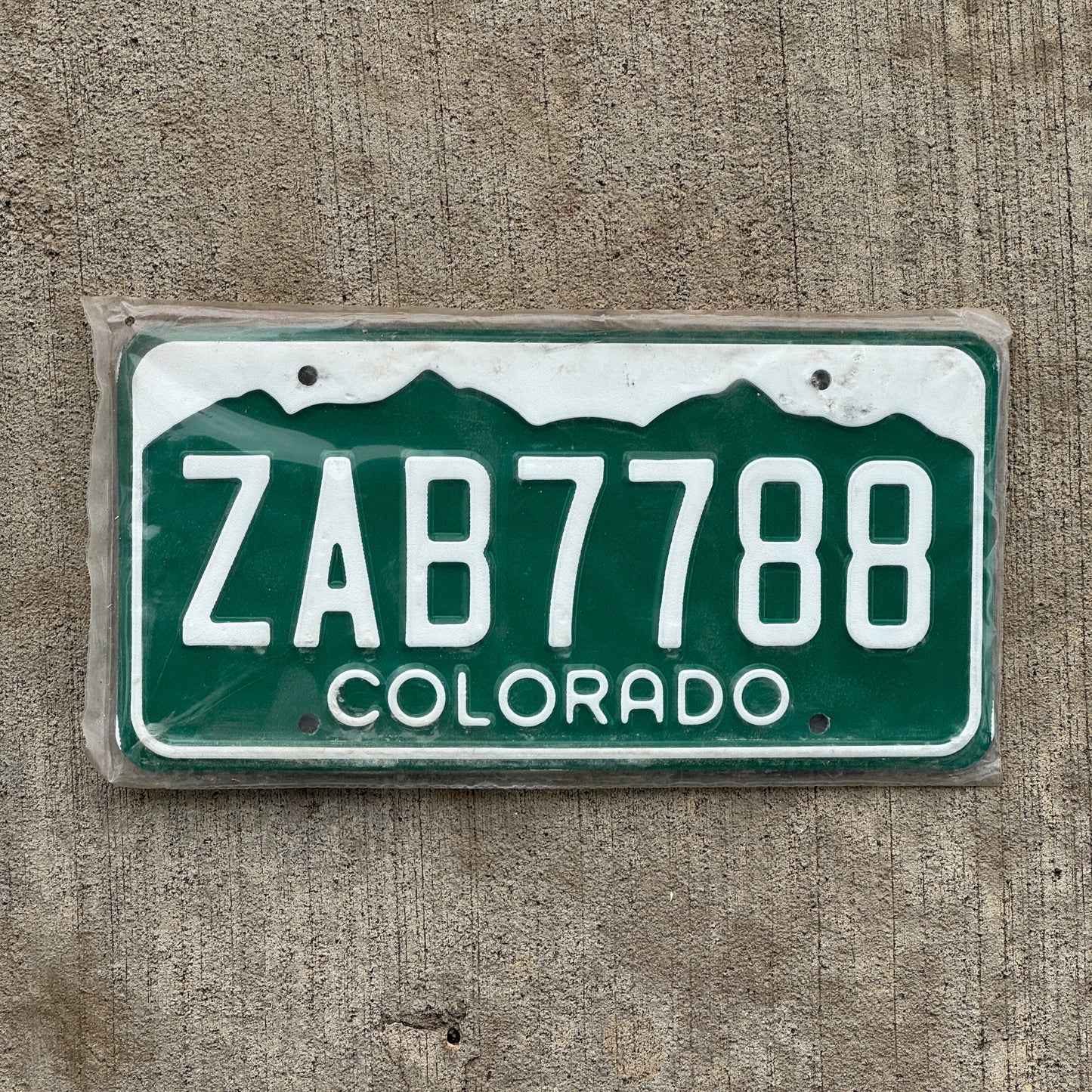 Photo of a 1977 Colorado License Plate Auto Tag Garage Decor Vintage New Old Stock NOS ZAB 7788 with original patina