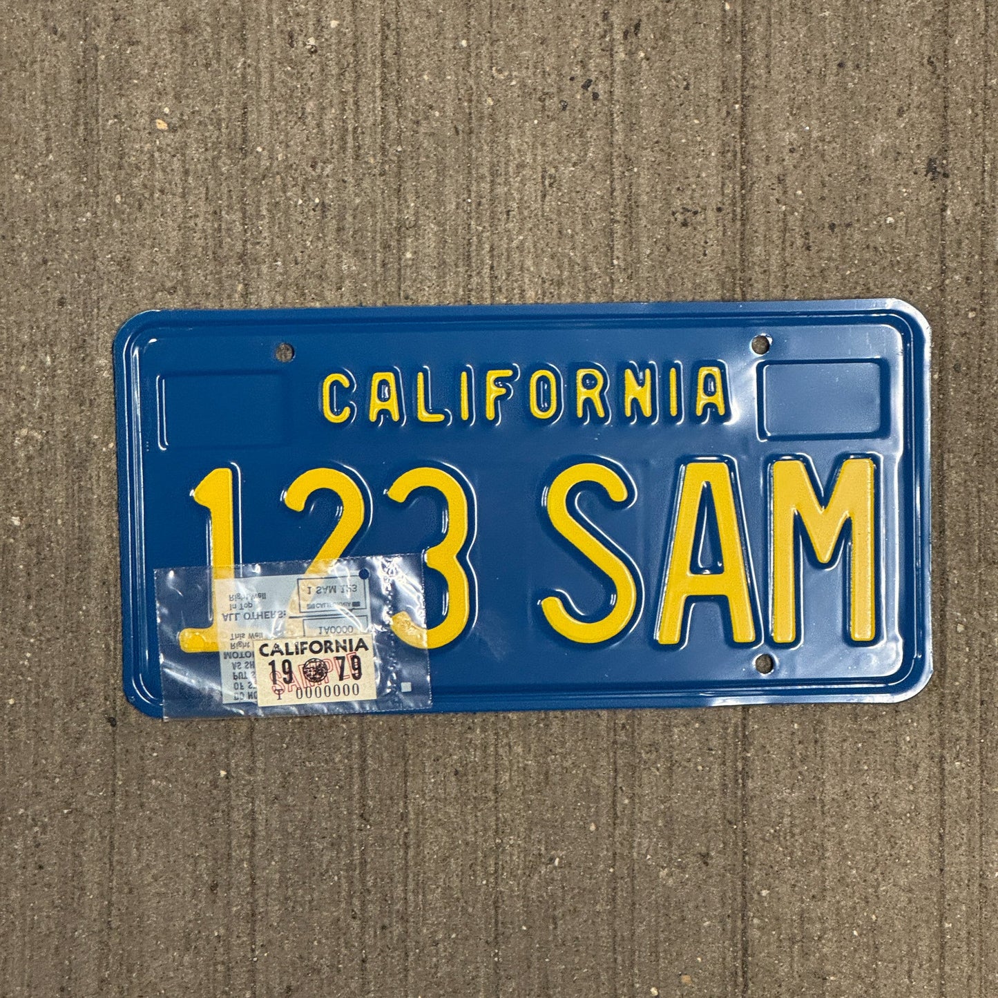 Photo of a 1979 California SAMPLE License Plate Auto Tag Garage Decor Vintage with Registration Sticker 123 SAM