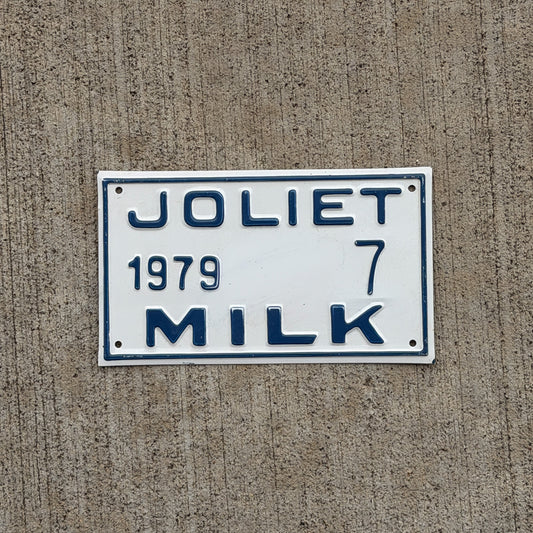 Photo of a 1979 Joliet Illinois Milk Vendor License Plate Auto Tag Garage Decor Vintage Dairy Milkman Lucky Number 7 with original patina