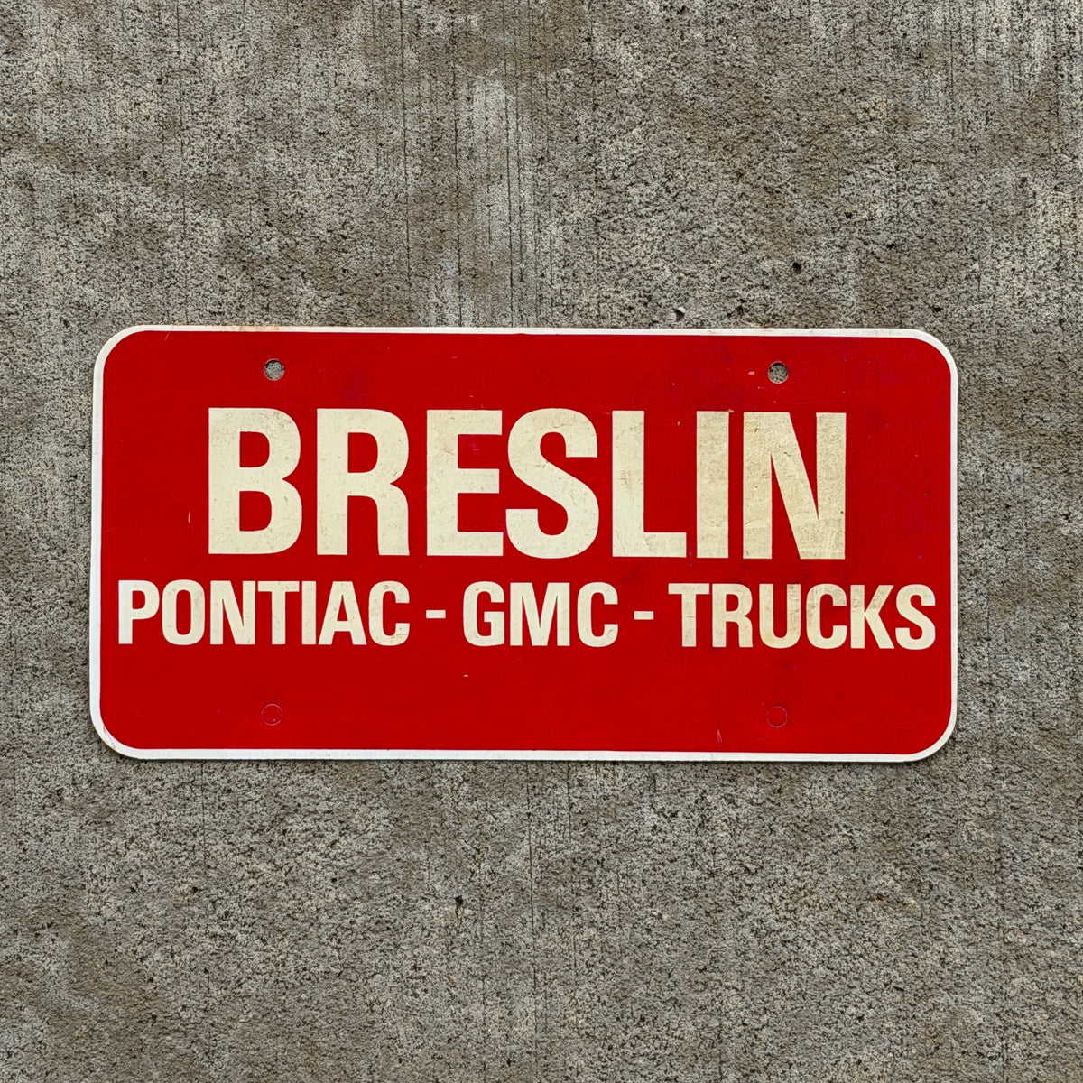 Photo of a 1980 Era Breslin Booster License Plate Auto Tag Garage Decor Vintage Pontiac GMC Trucks Plastic with original patina