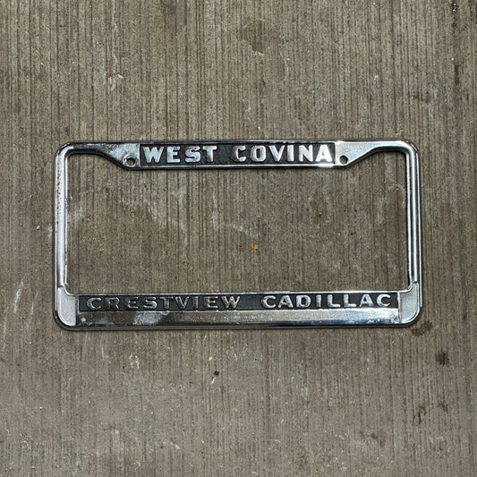Photo of a 1980 Era California License Plate Frame Auto Tag Garage Decor Vintage West Covina Metal Crestview Cadillac with original patina