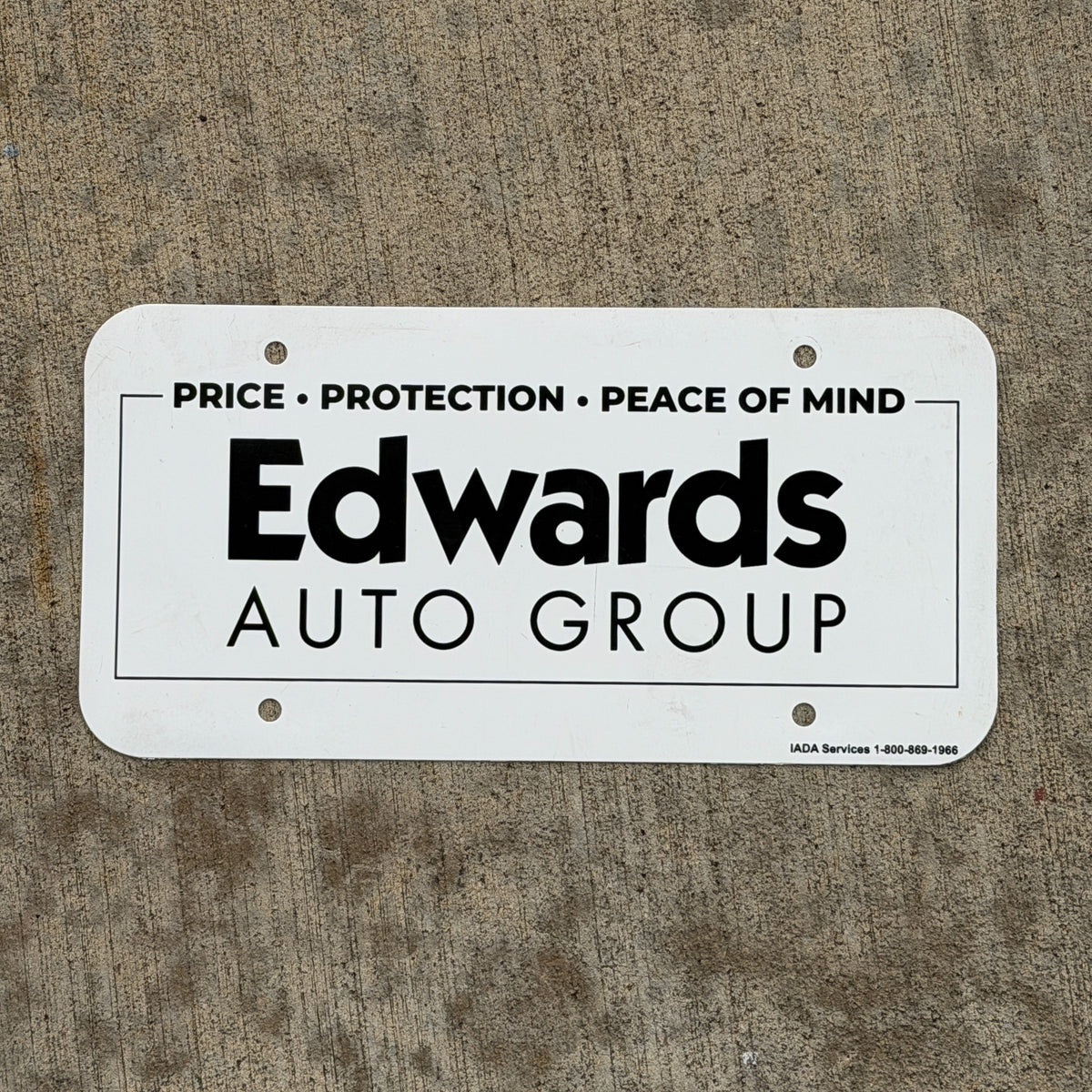 Photo of a 1980 Era Edwards Auto Group Booster License Plate Auto Tag Garage Decor Vintage Plastic with original patina