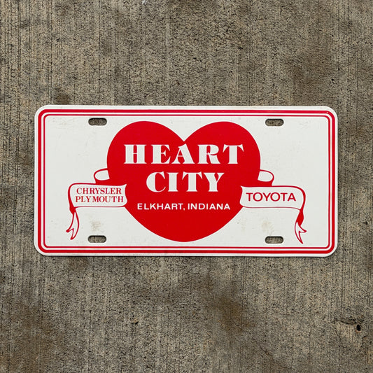 Photo of a 1980 Era Elkhart Indiana Booster License Plate Auto Tag Garage Decor Vintage Heart City Chrysler Plymouth Toyota Plastic with original patina