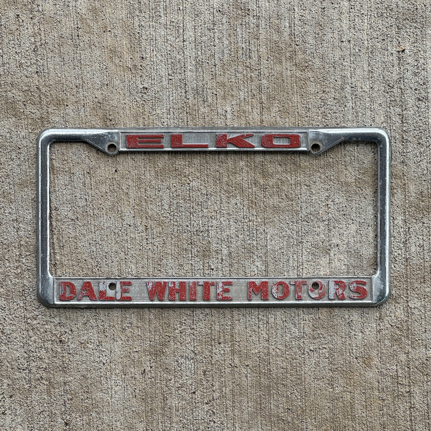 Photo of a 1980 Era ELKO Dale White Motors Nevada License Plate Frame Auto Tag Garage Decor Vintage Dodge Toyota with original patina