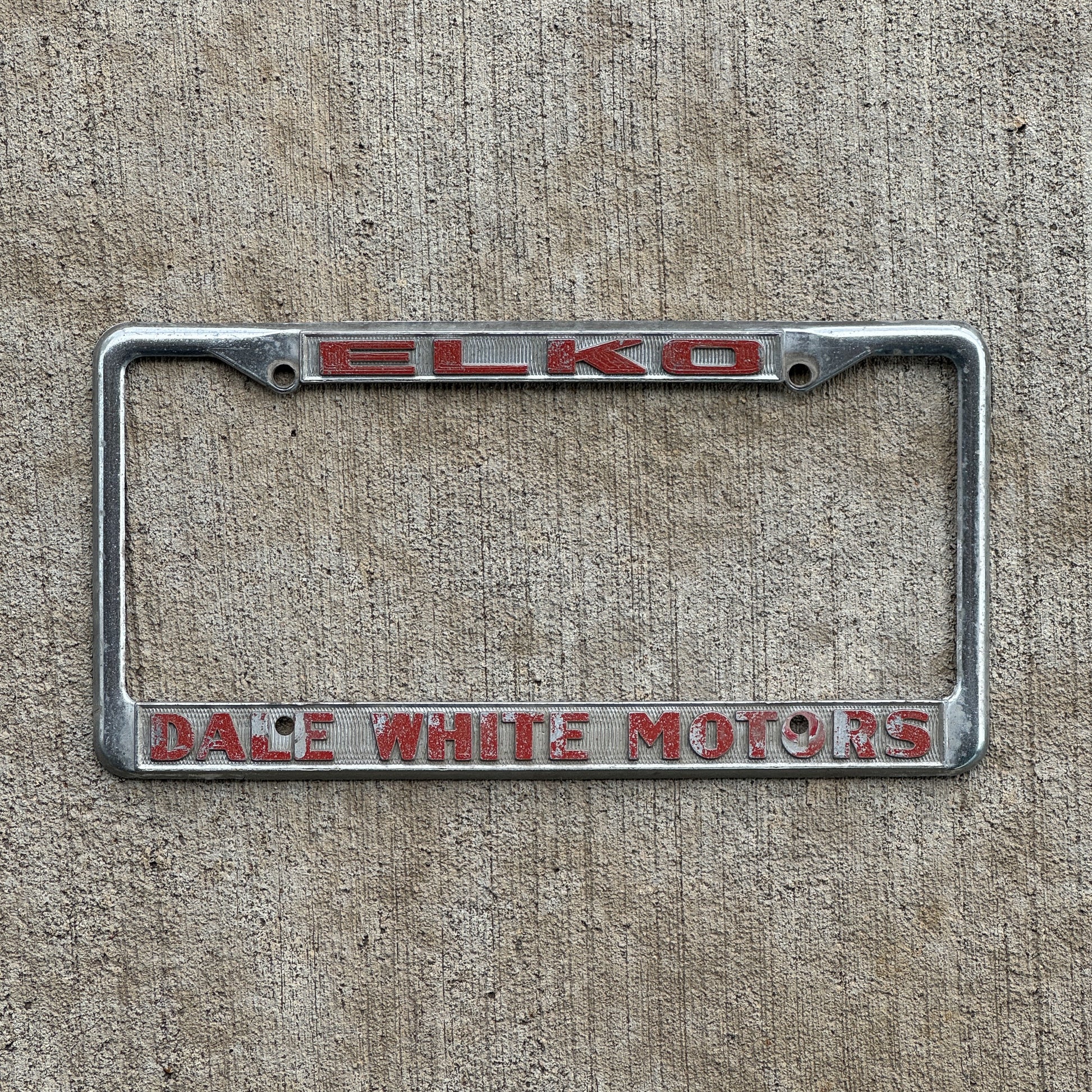Photo of a 1980 Era ELKO Dale White Motors Nevada License Plate Frame Auto Tag Garage Decor Vintage Dodge Toyota with original patina