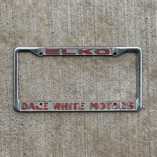 Photo of a 1980 Era ELKO Dale White Motors Nevada License Plate Frame Auto Tag Garage Decor Vintage Dodge Toyota with original patina