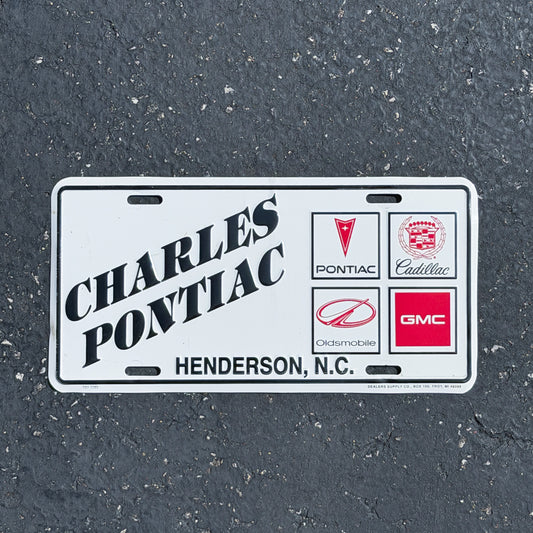 Photo of a 1980 Era Henderson North Carolina Booster License Plate Auto Tag Garage Decor Vintage
 Charles Pontiac Cadillac Oldsmobile GMC Metal with original patina