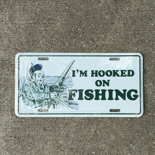 Photo of a 1980 Era I'm Hooked On Fishing Booster License Plate Auto Tag 2 Vintage Garage
 Fish Gift Metal with original patina