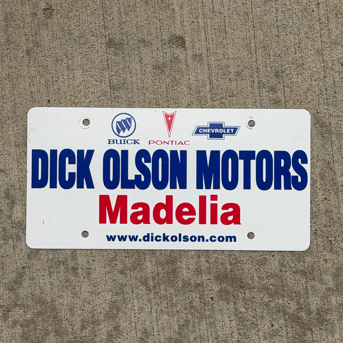 Photo of a 1980 Era Madelia Minnesota Booster License Plate Auto Tag Garage Decor Vintage Dick Olson Motors Buick Pontiac Chevy Plastic with original patina