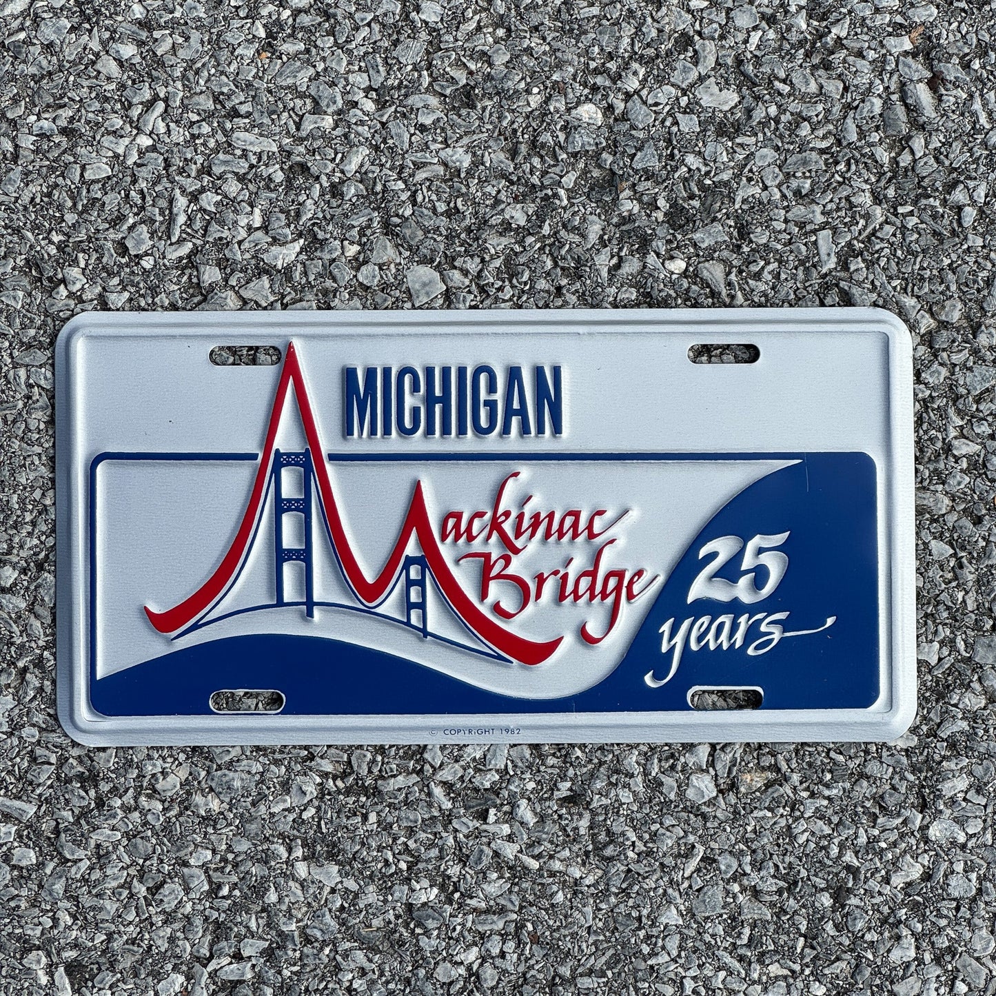 Photo of a 1982 Michigan Booster License Plate Auto Tag Garage Decor Vintage Mackinac Bridge 25th Anniversary