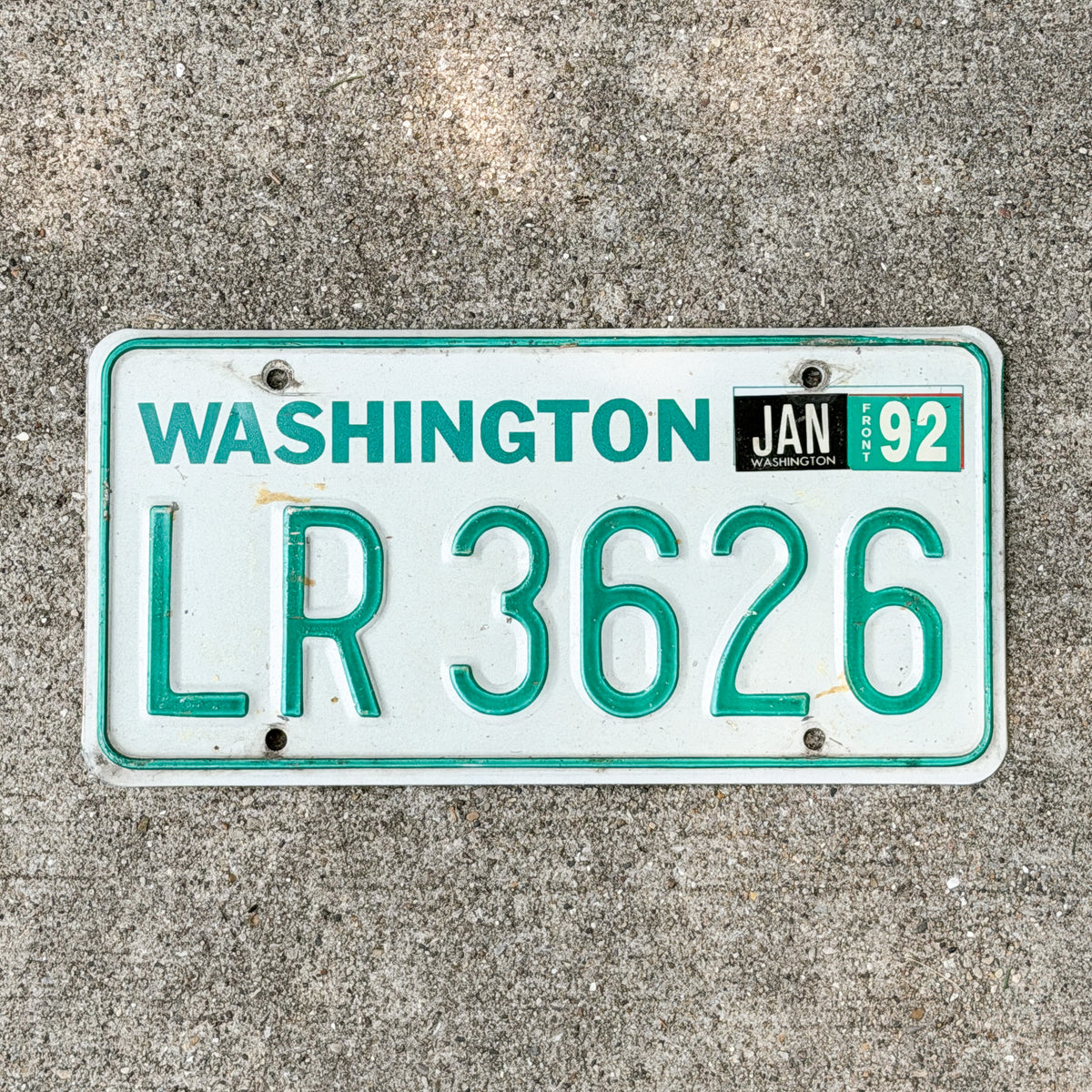 Photo of a 1984 Washington Truck License Plate Auto Tag with number LR 3626 on a concrete background that is DMV clear for road use.
