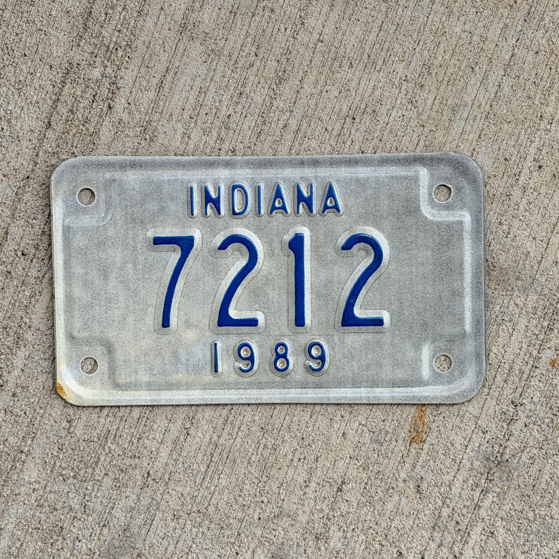 Photo of a 1989 Indiana Motorcycle License Plate Auto Tag Garage Decor Vintage Low Number Four Digit 7212 with original patina