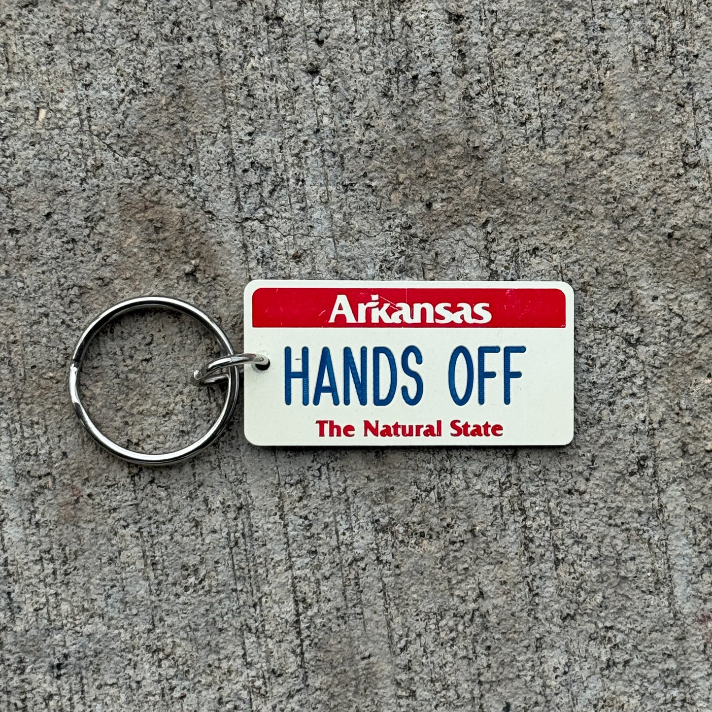 Photo of a 1990 Era Arkansas Keychain Auto Tag Garage Decor Vintage HANDS OFF with original patina