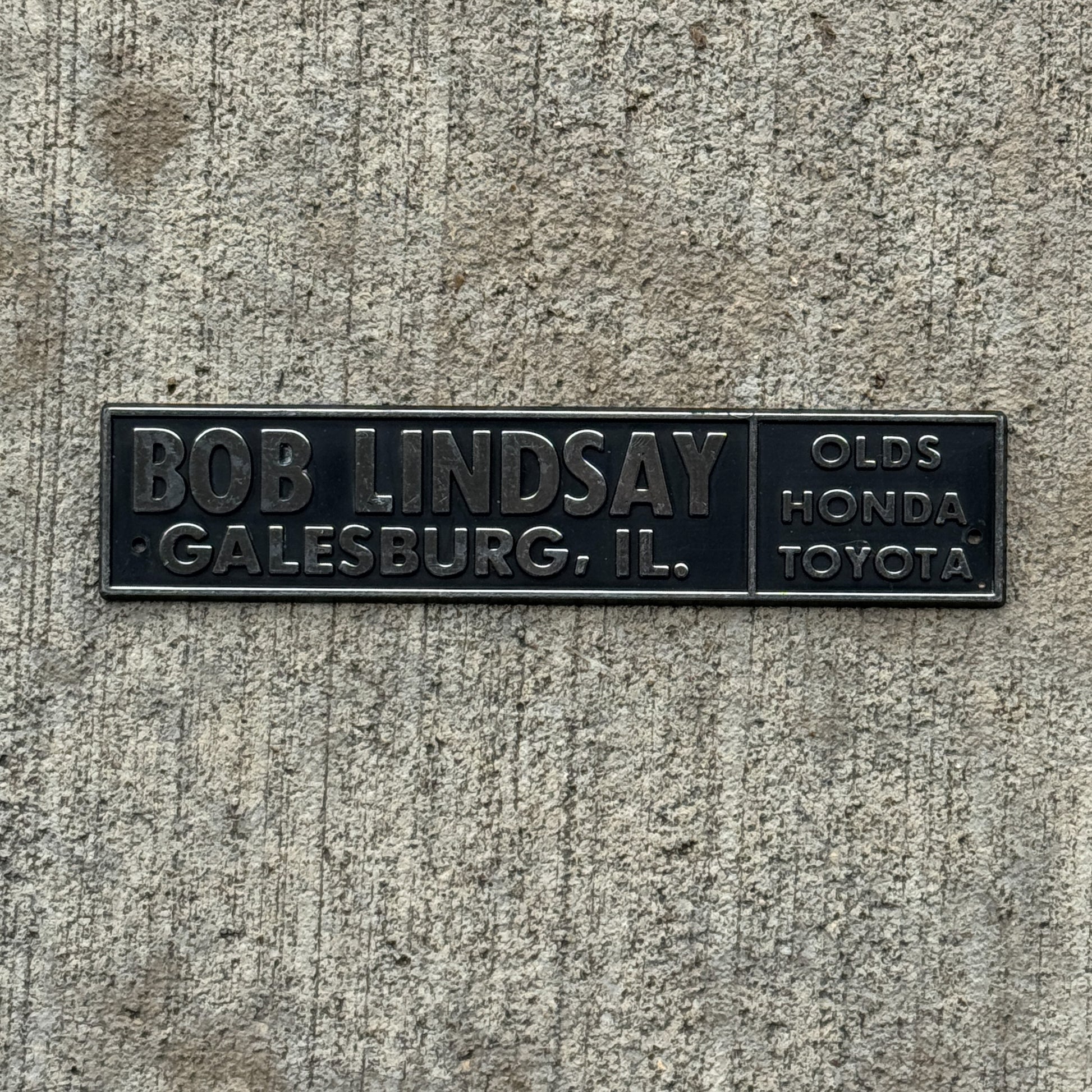 Photo of a 1990 Era Bob Lindsay Galesburg Illinois Dealer Badge Emblem Auto Tag Garage Decor Vintage Olds Honda Toyota Dealership with original patina