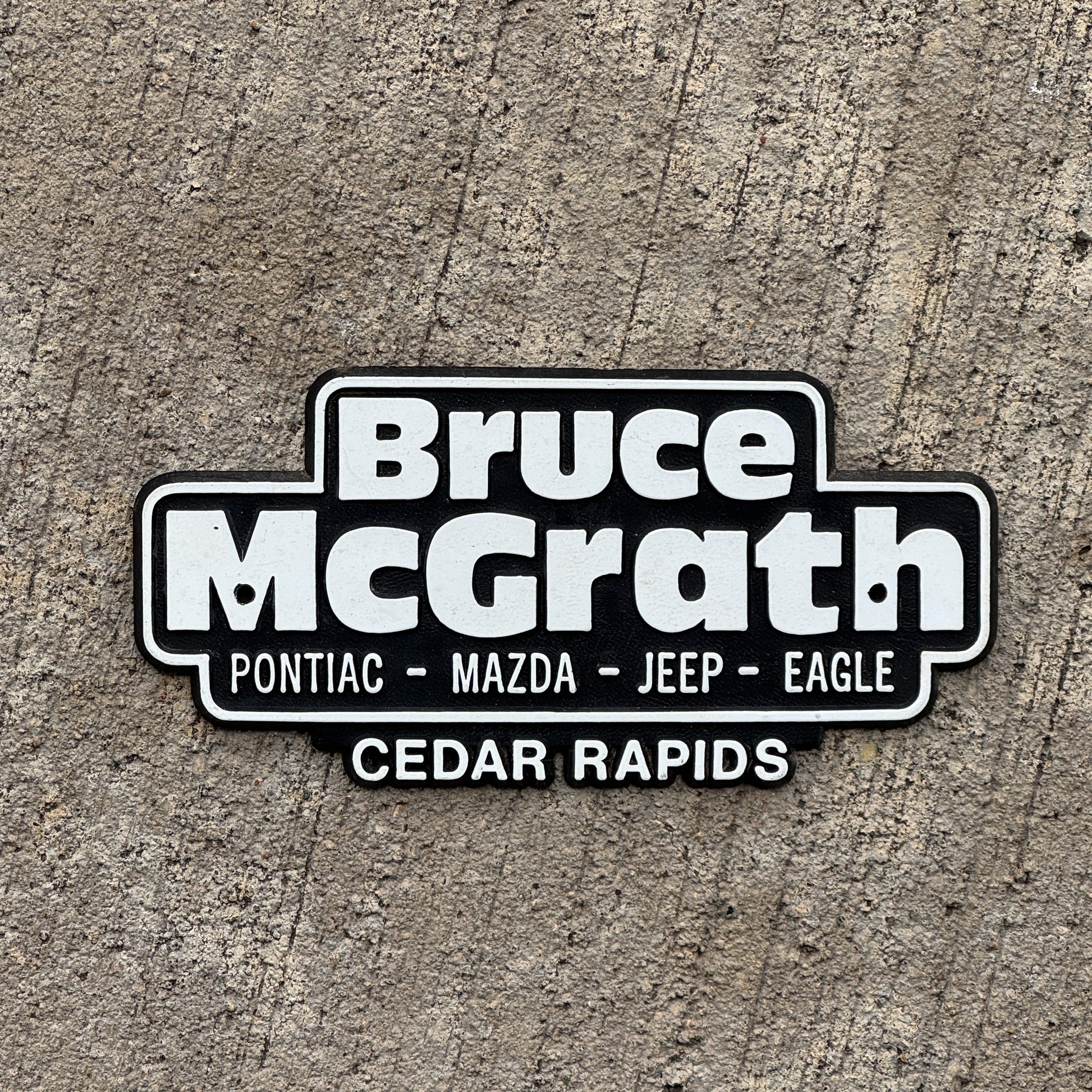 Photo of a 1990 Era Bruce McGrath Cedar Rapids Iowa Dealer Badge Emblem Auto Tag Garage Decor Vintage Pontiac Mazda Plastic Dealership with original patina