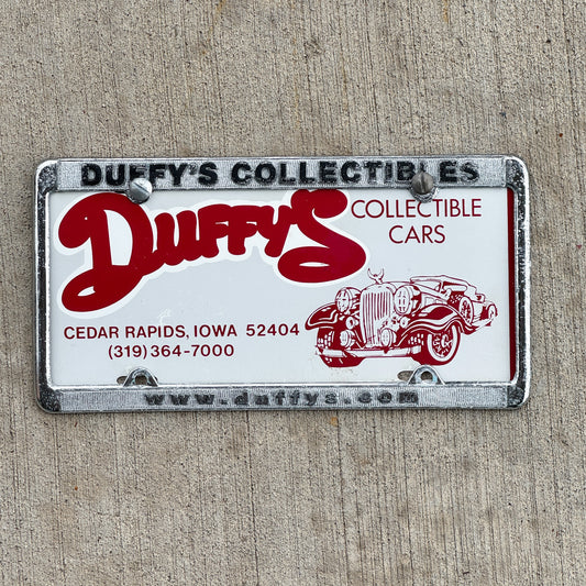 Photo of a 1990 Era Duffy's Collectible Cars Iowa Booster License Plate Auto Tag Garage Decor Vintage With Frame with original patina