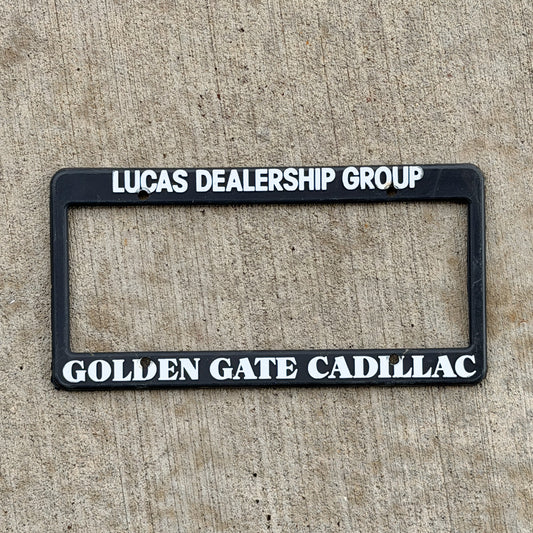 Photo of a 1990 Era Golden Gate Cadillac California Dealer License Plate Frame Auto Tag Garage Decor Vintage
 Plastic Lucas Dealership Group with original patina