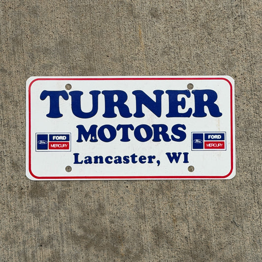 Photo of a 1990 Era Lancaster Wisconsin Booster License Plate Auto Tag Garage Decor Vintage Turner Motors Ford Mercury Plastic with original patina